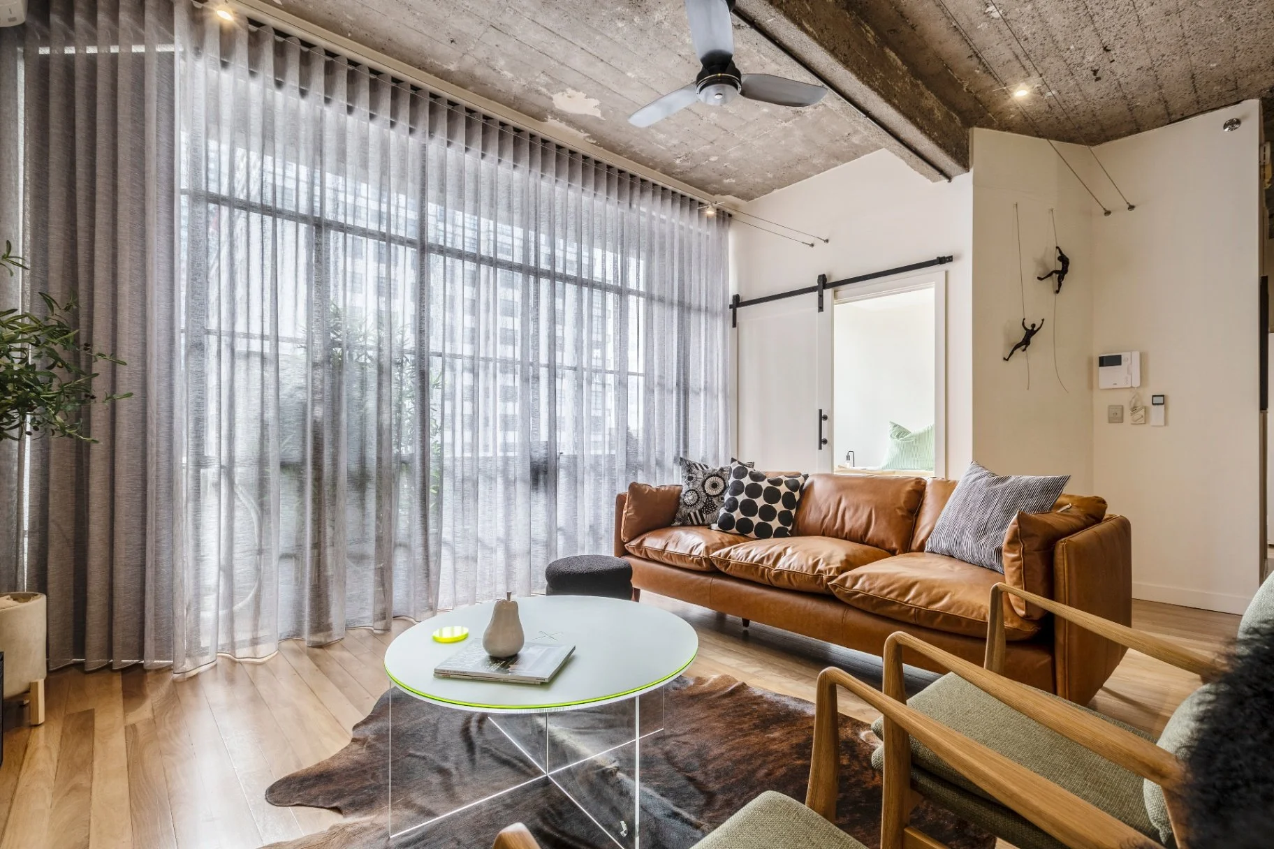 Industrial apartment interior in Melbourne CBD with warehouse windows and scandi furniture, concrete ceilings and exposed lighting.