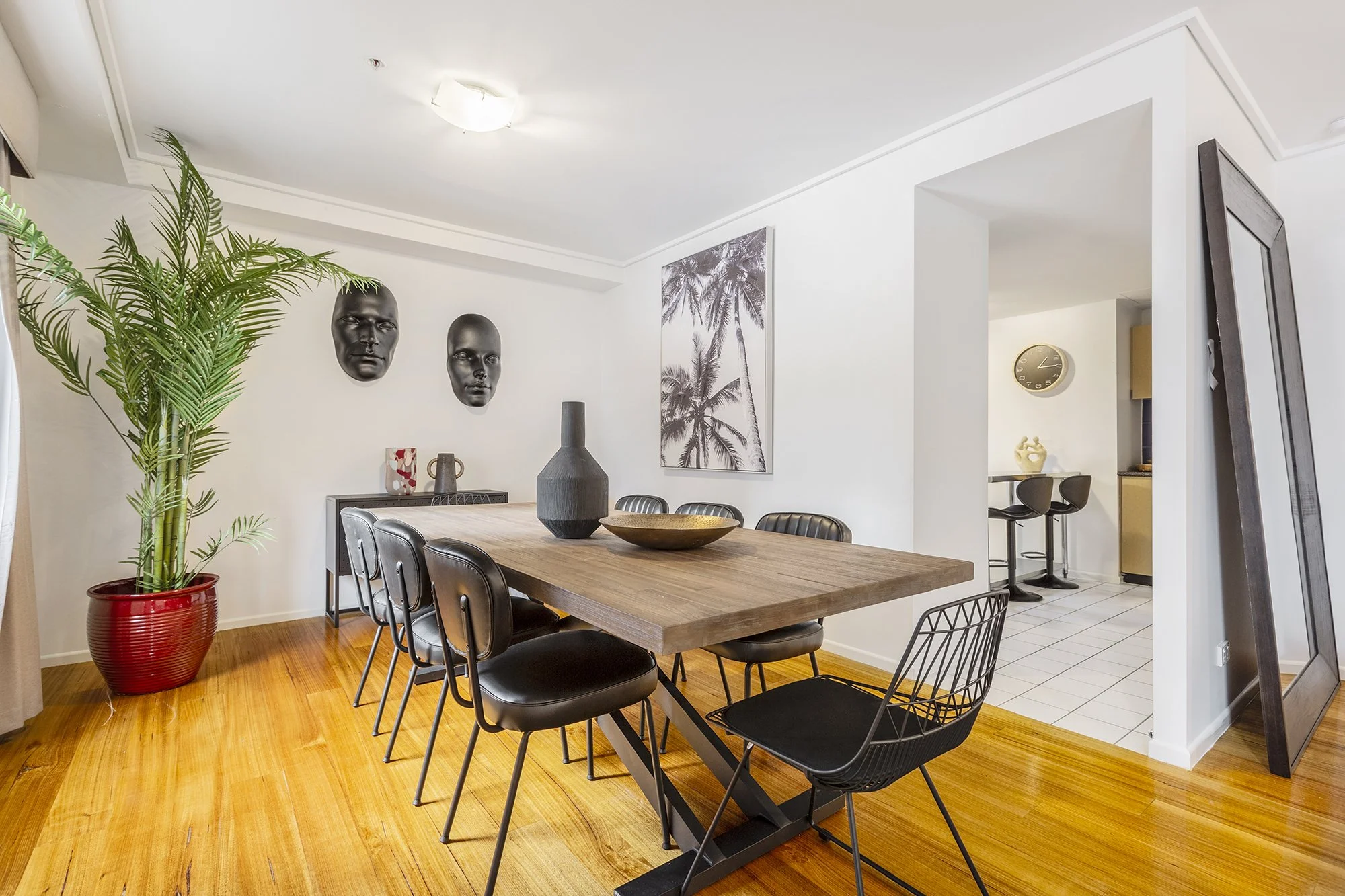 Eclectic Melbourne CBD Airbnb dining area with bold decor, palm tree artwork and wooden dining table