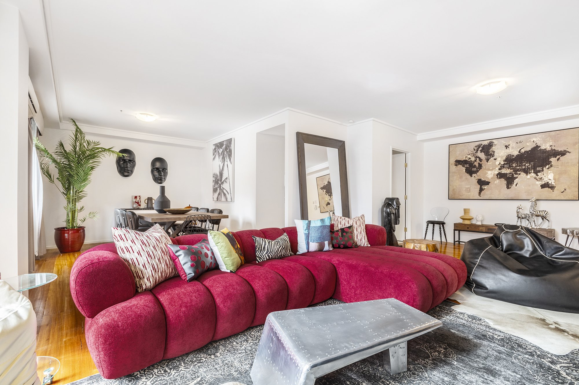 Bold, eclectic living room in a Melbourne CBD Airbnb with a red modular sofa and gallery wall