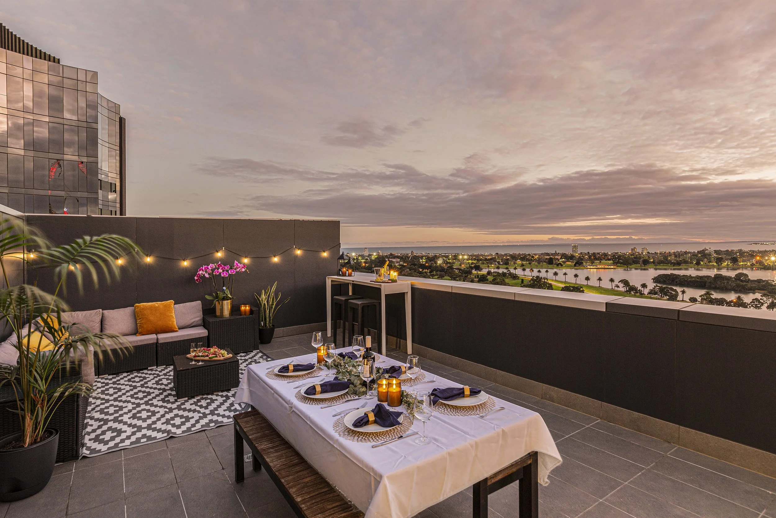 Airbnb dusk photography showing a well appointed balcony complete with dining table setup, and bay views