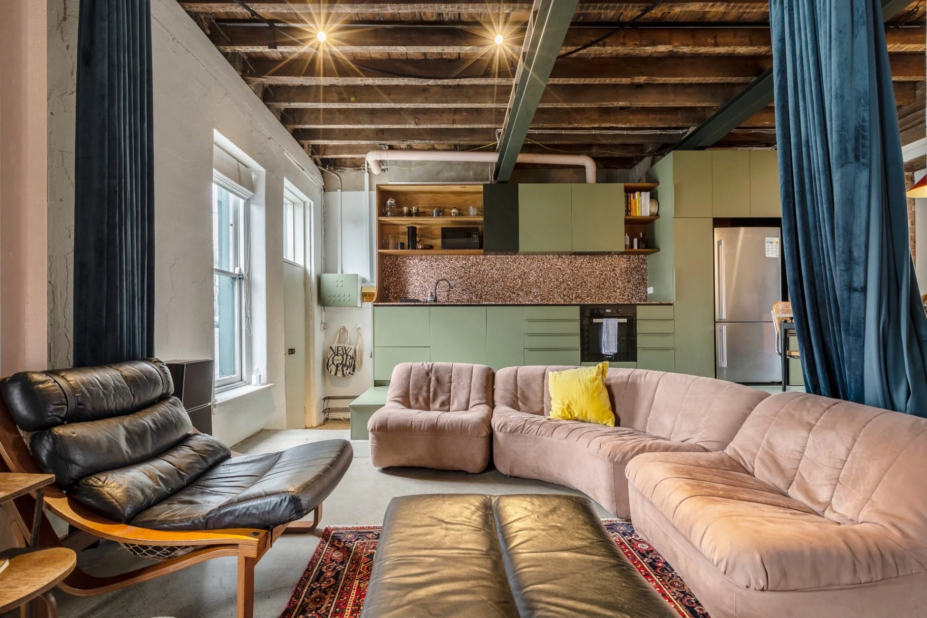 Rustic industrial interior of a North Melbourne Airbnb apartment with exposed beams, retro furnishings and a sage green kitchen.