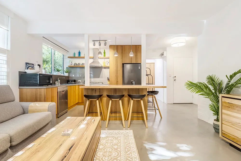Modern open plan St Kilda Airbnb with wooden kitchen and concrete floors, professionally photographed by Andrew Paranavitana