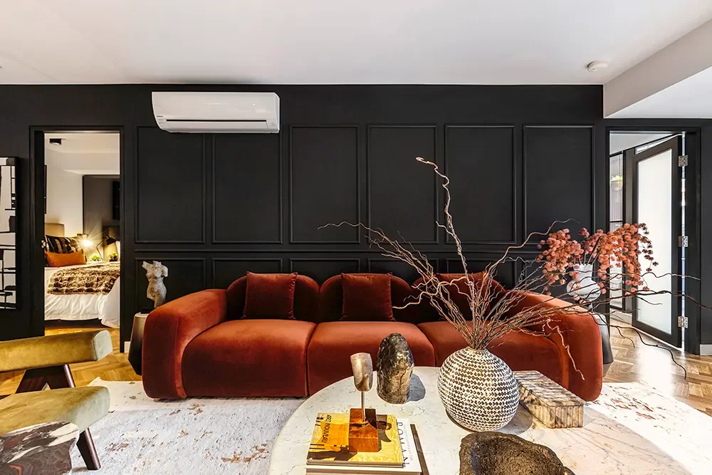 Modern living room on Jane Bell Lane with a burnt orange couch and black feature wall, highlighting expert interior photography.
