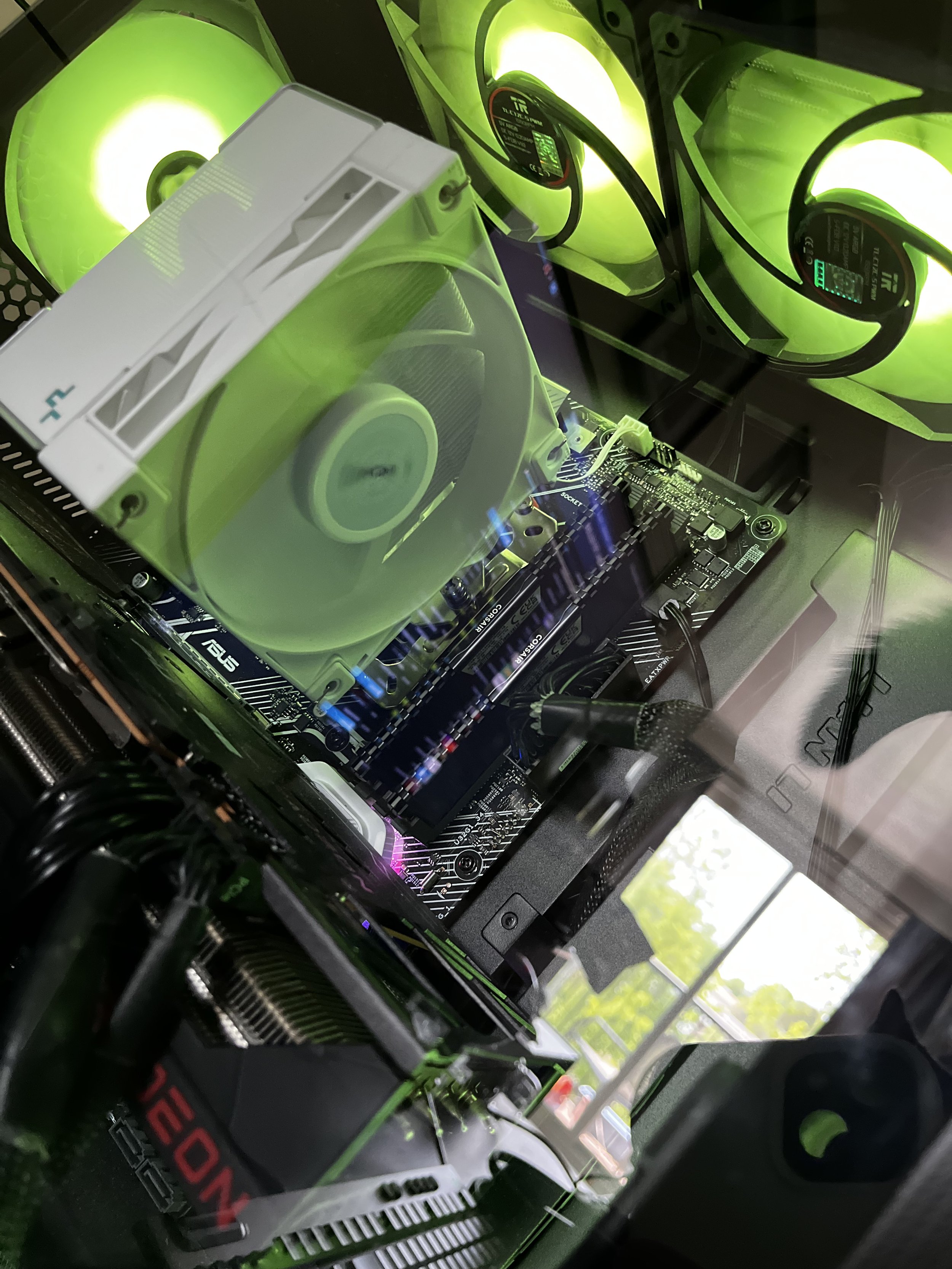 Inside a gaming or high-performance computer with green LED cooling fans, a large white CPU cooler, black motherboard, and various connected components.