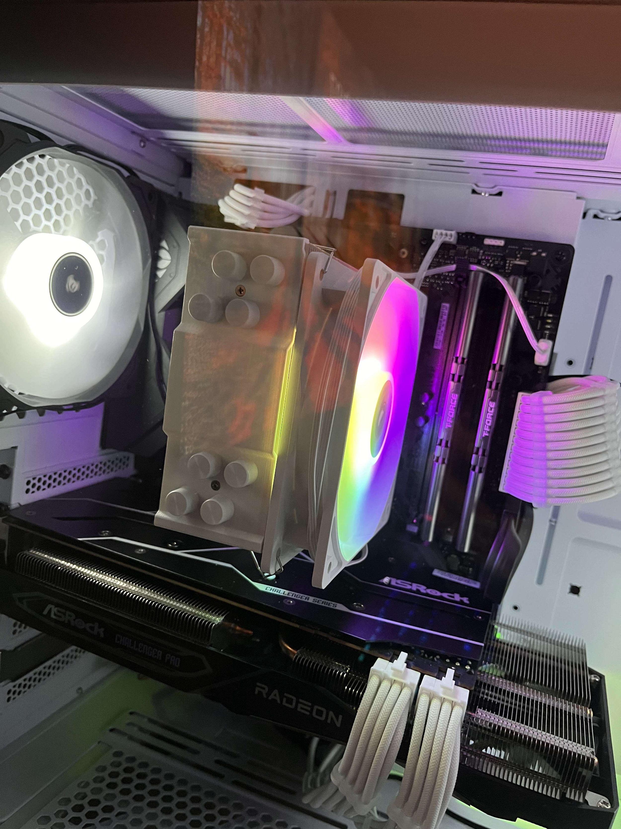 Inside a computer case showing a cooling fan, a CPU cooler with RGB lighting, RAM sticks, and a graphics card with brand labels.
