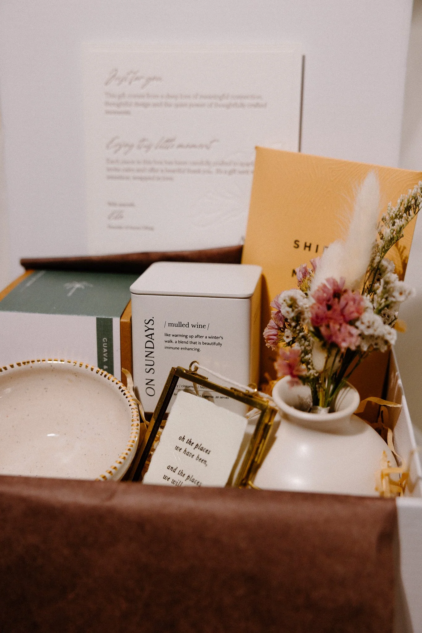A beige cardboard box casting shadows of leaves on a white surface.