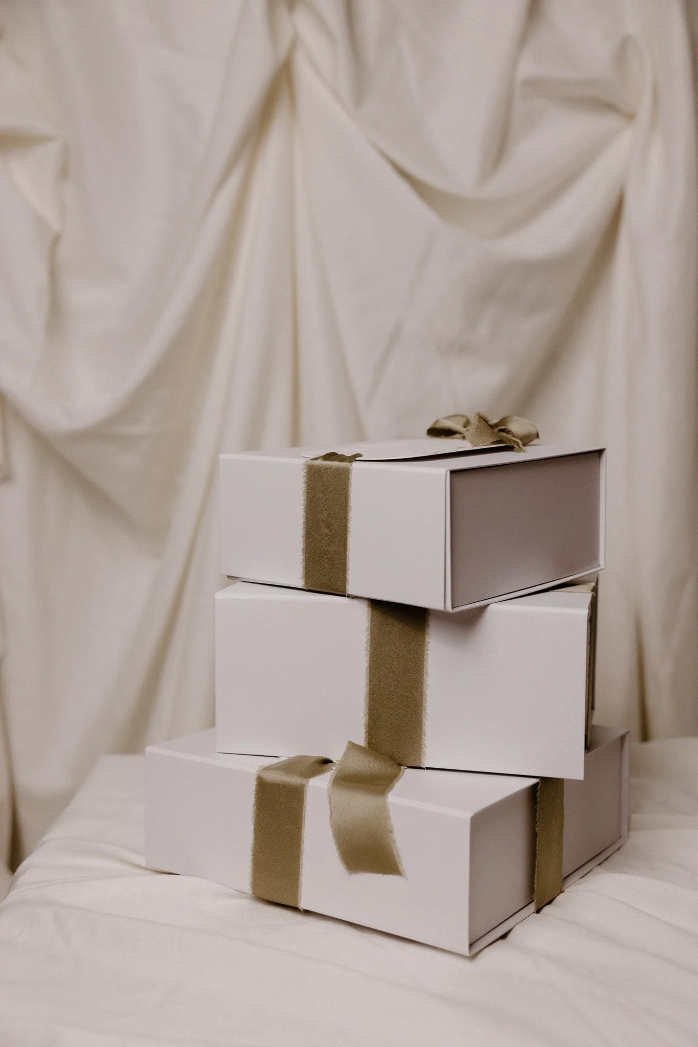 Three beige cardboard boxes with white labels on a dark wooden surface, with sunlight and shadow play.