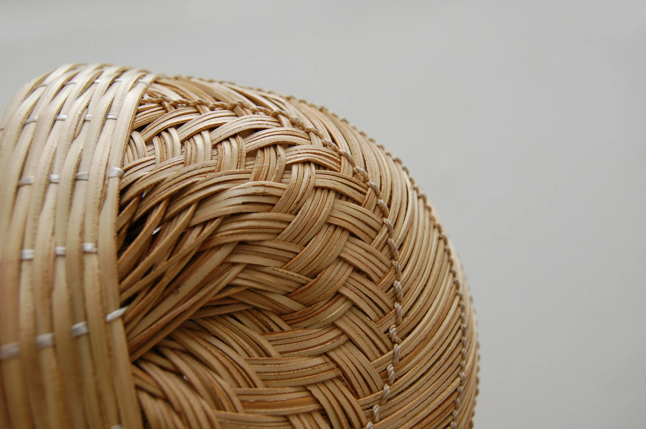 Close-up of woven wicker or rattan basket with a natural beige color, showing intricate weaving patterns and texture.