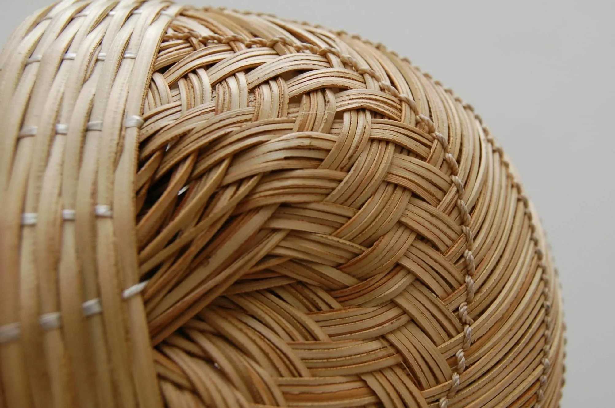 Close-up of woven wicker or rattan basket with a natural beige color, showing intricate weaving patterns and texture.