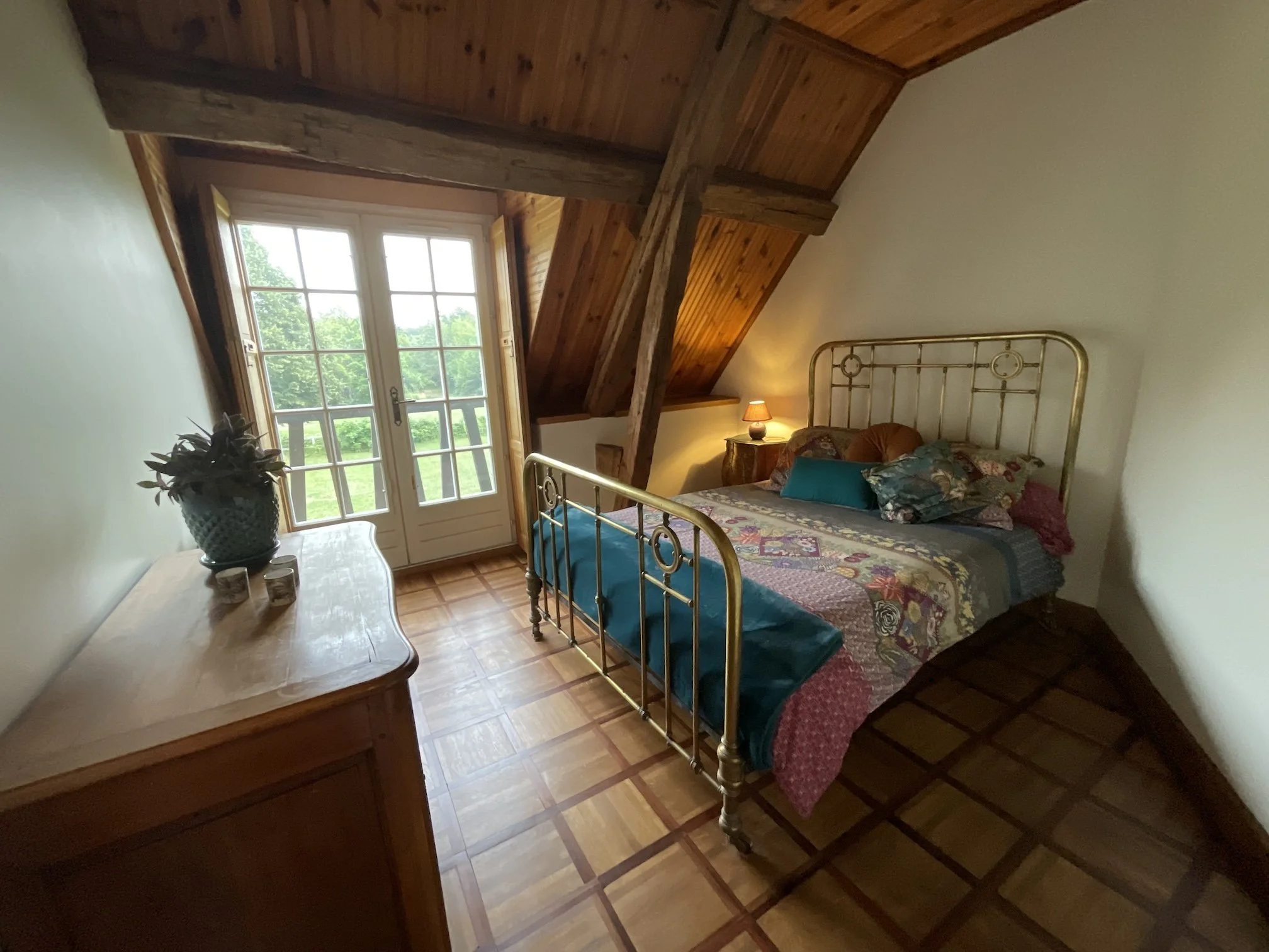 chambre double avec lit en laiton doré et grande baie vitrée à l'étage du gîte de la Boursicauderie