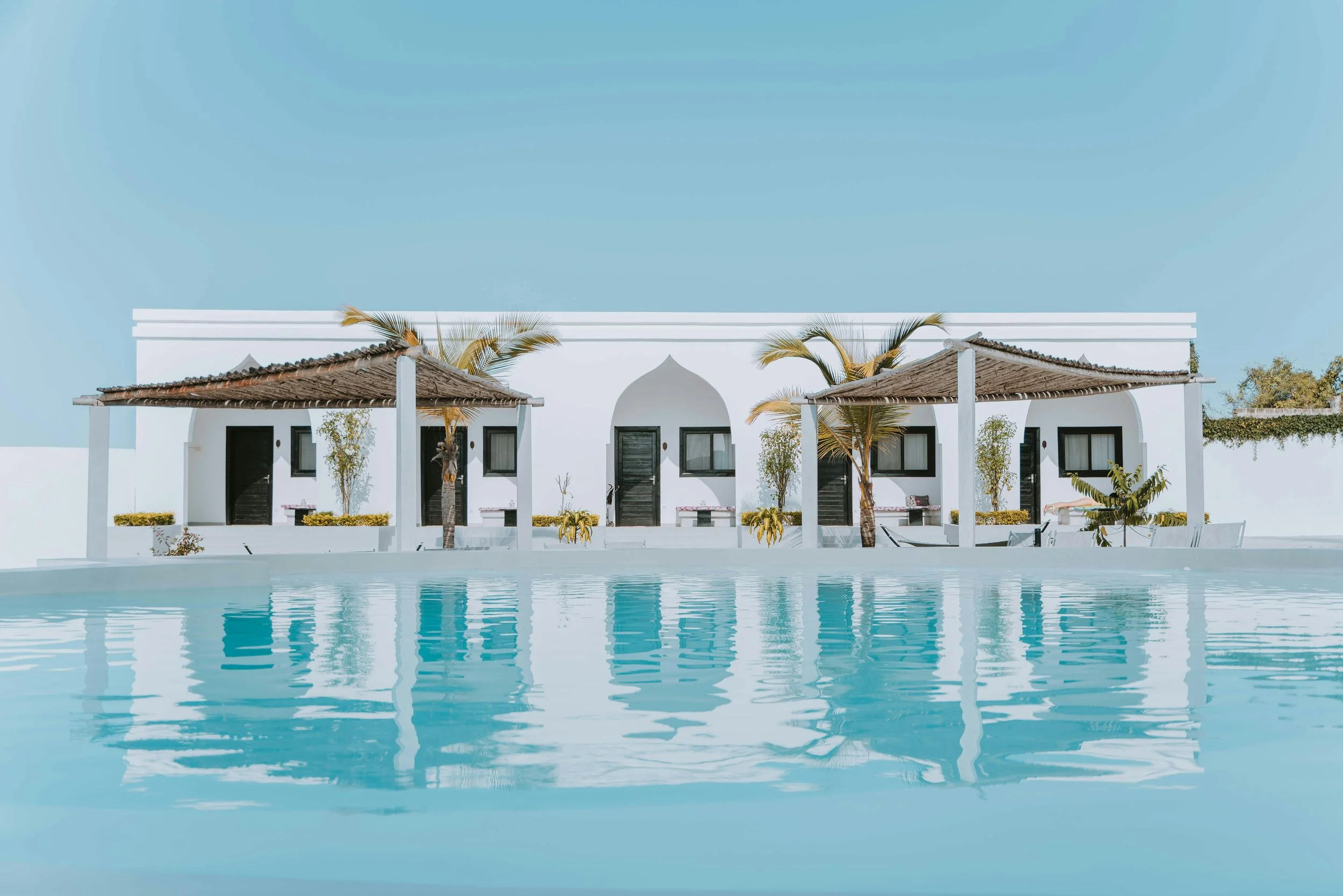 White oceanfront villas with shaded terraces and palm trees