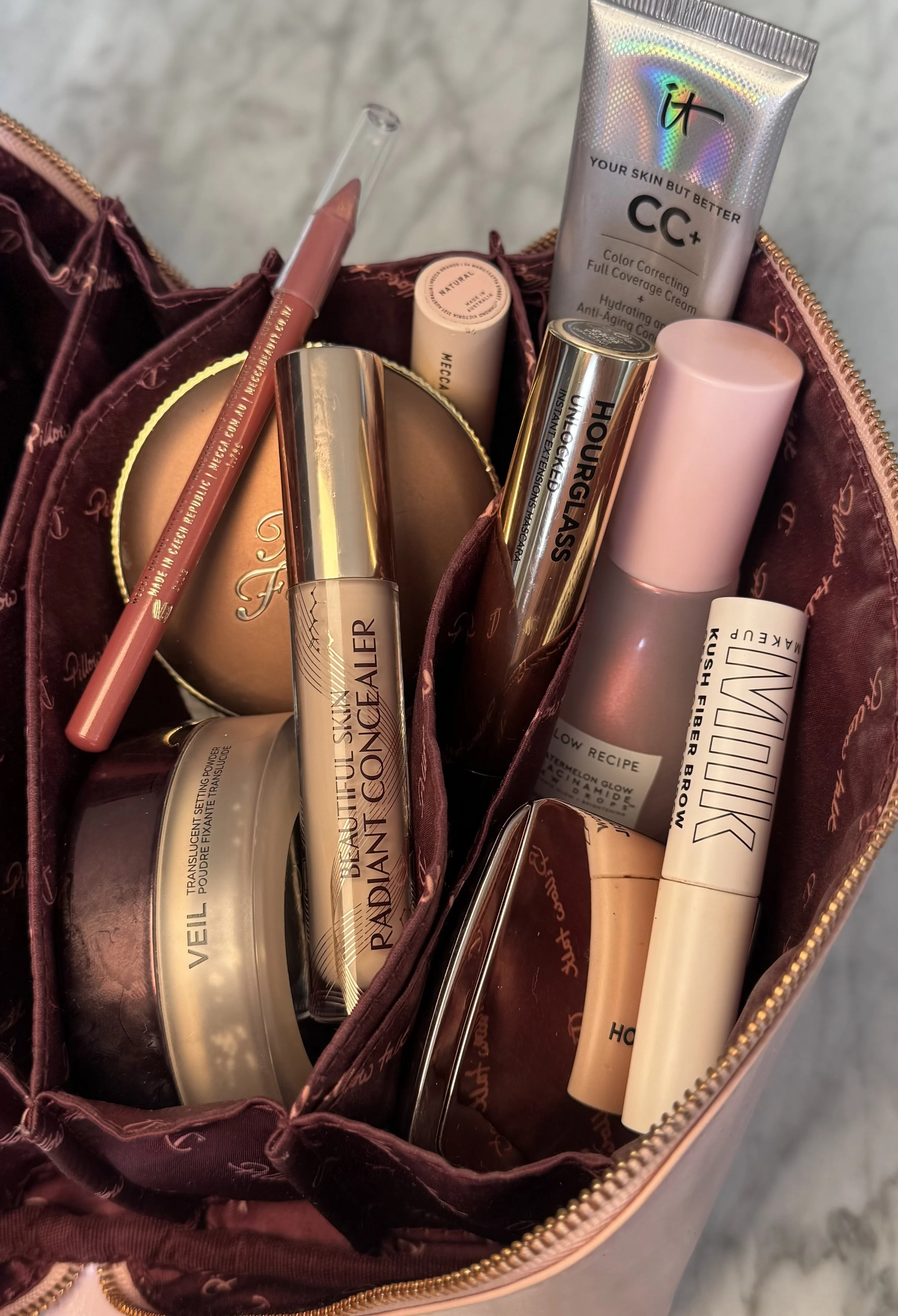 Foundation, concealer, blush and lip products in a makeup bag for a one on one makeup lesson