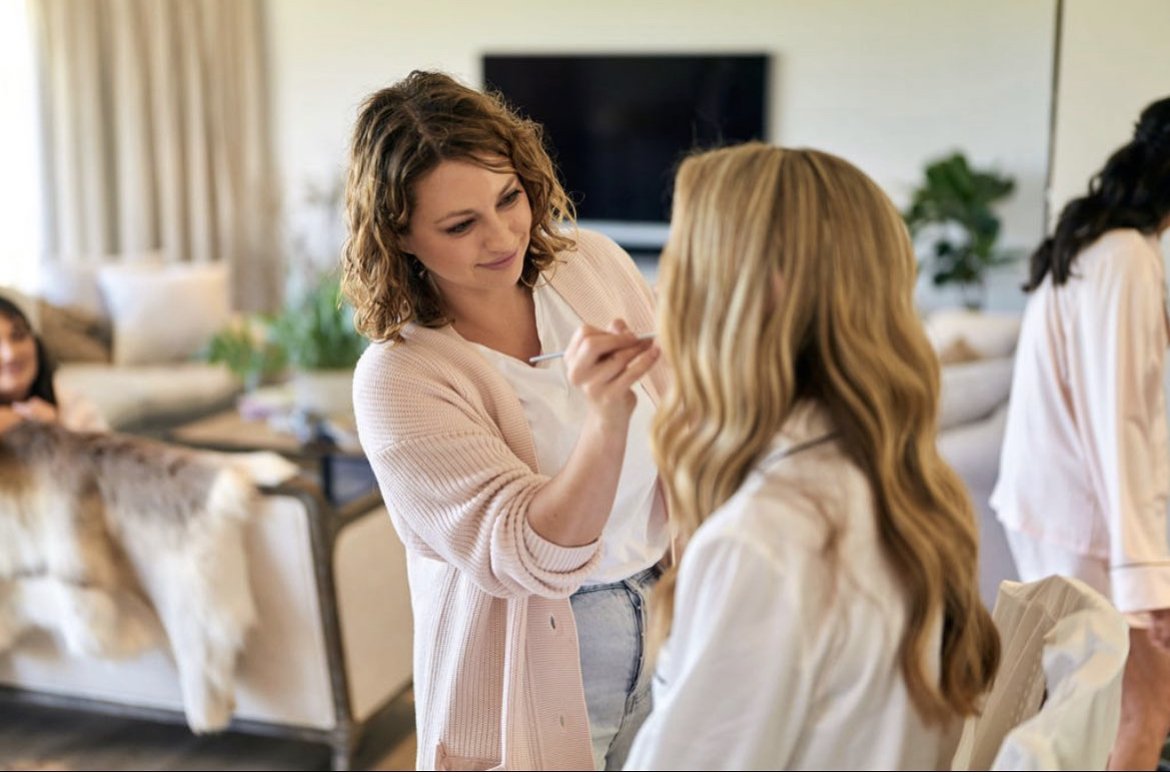makeup artist applying lipstick on the bride at her trial