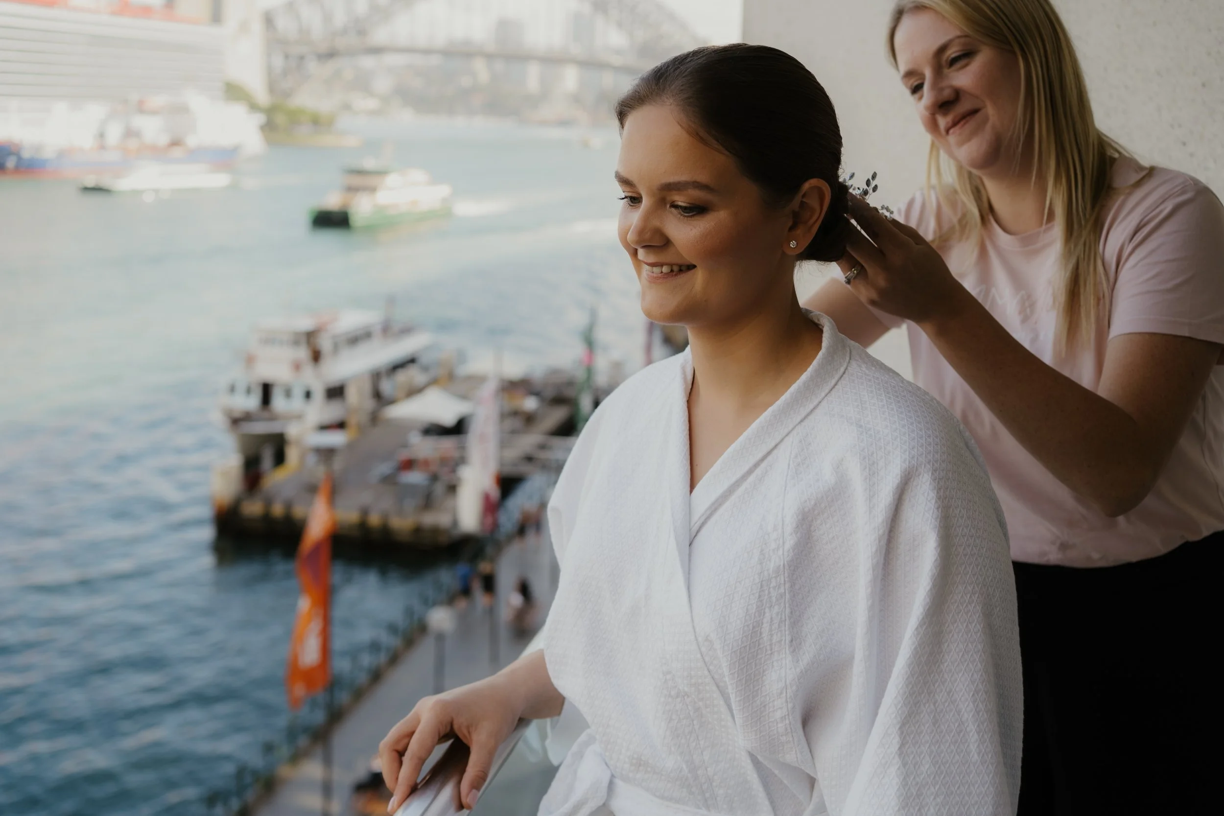 hair stylist doing brides hair with Sydney Harbour Bridge in background