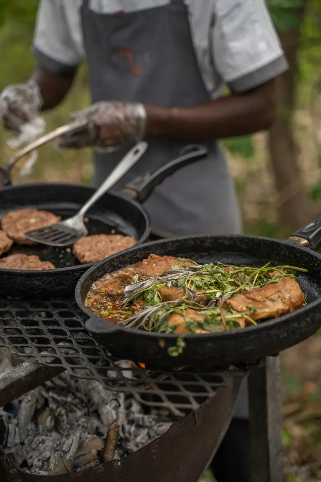 Chef preparing bush cuisine over open coals with fresh herbs, Thorntree River Lodge, Zambia