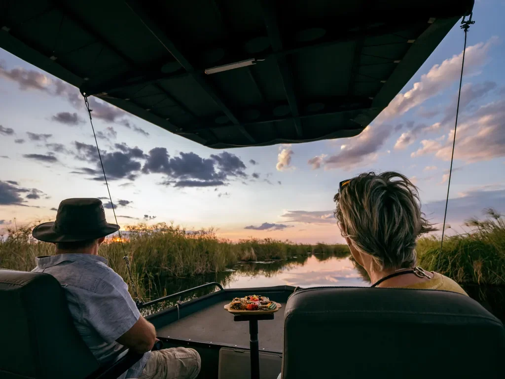 Sunset boat safari from DumaTau, guests cruising the reed-lined channels of the Linyanti in northern Botswana.