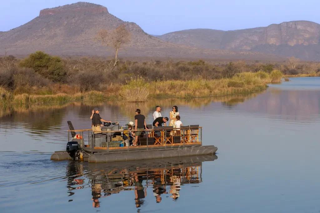 Miss Mara boat cruising the lodge dam at Marataba Safari Lodge, Waterberg mountains backdrop
