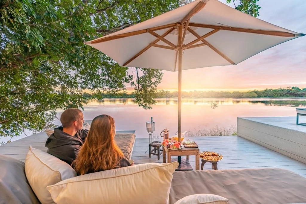Couple sharing a riverfront breakfast on a private deck at Chinzombo, South Luangwa National Park, Zambia