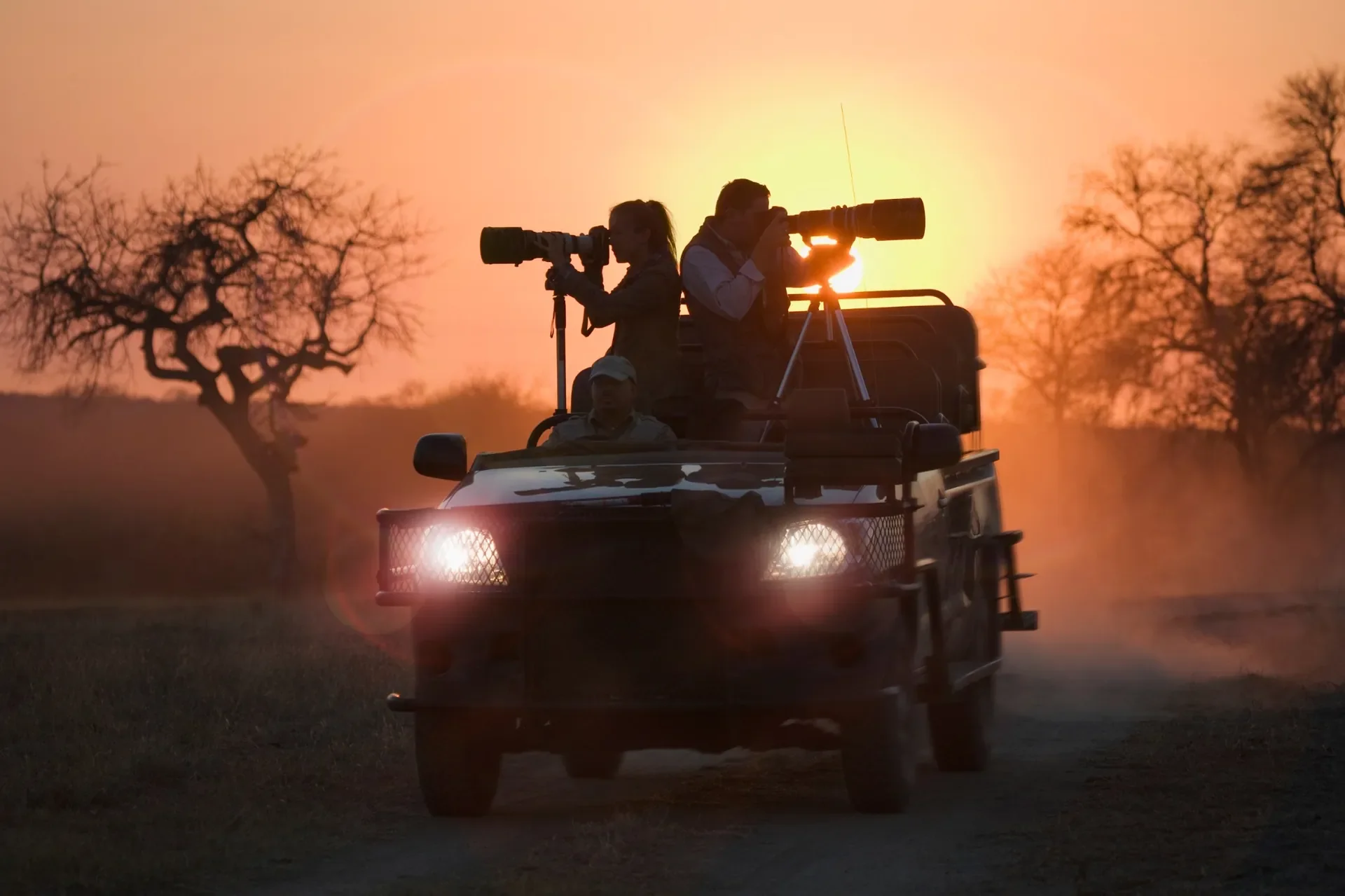 Photographers on a Phinda game drive vehicle shooting at sunset in South Africa