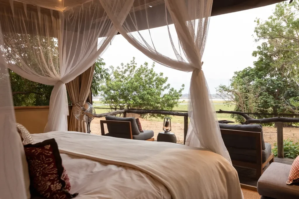 Tented suite bedroom with mosquito net and open views to the Zambezi floodplain at Little Ruckomechi, Mana Pools National Park, Zimbabwe