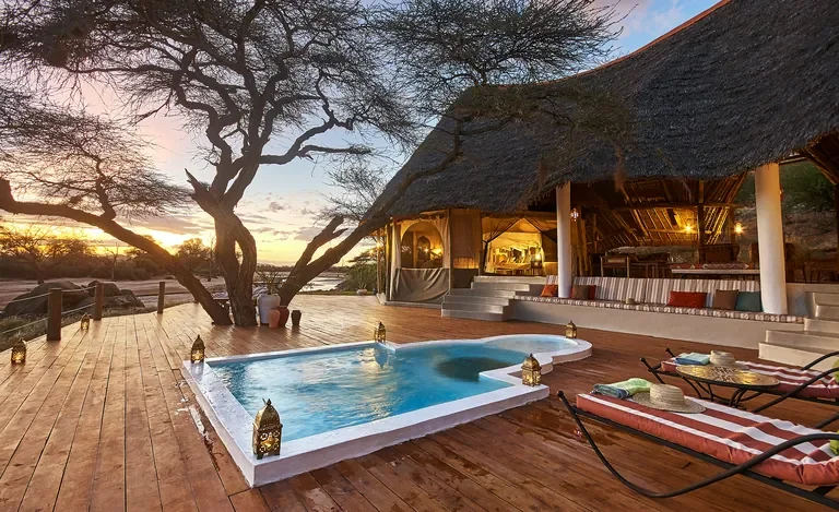 Thatched veranda with loungers and plunge pool overlooking arid Samburu plains at Sasaab, Kenya