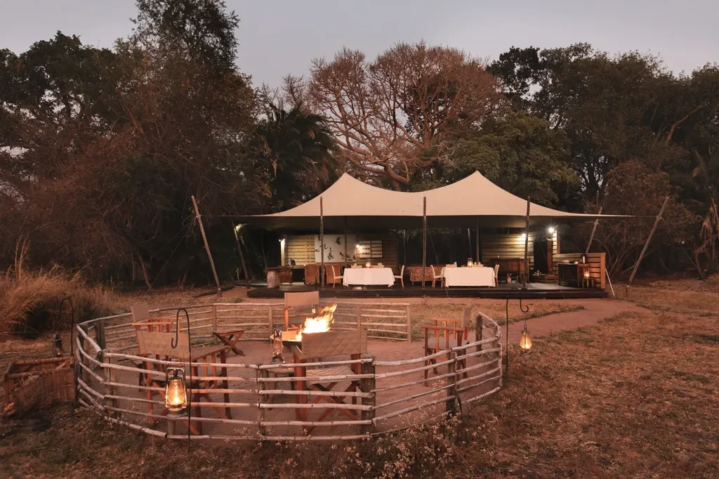 Busanga Bush Camp exterior with firepit and canvas mess tent at twilight, Kafue National Park Zambia