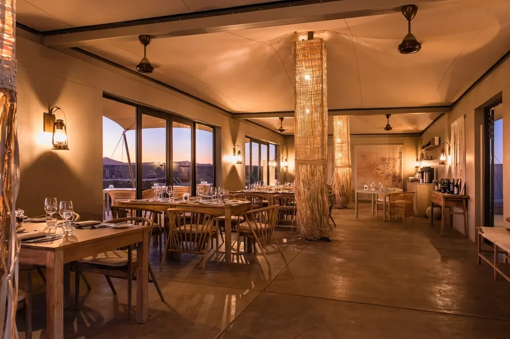 Kulala Desert Lodge dining room at sunset with lanterns and desert views