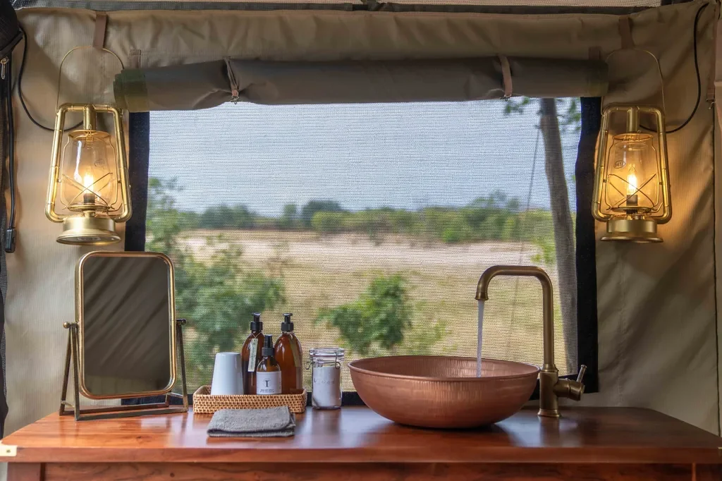 Copper basin vanity and vintage lanterns inside Time + Tide Luwi safari tent