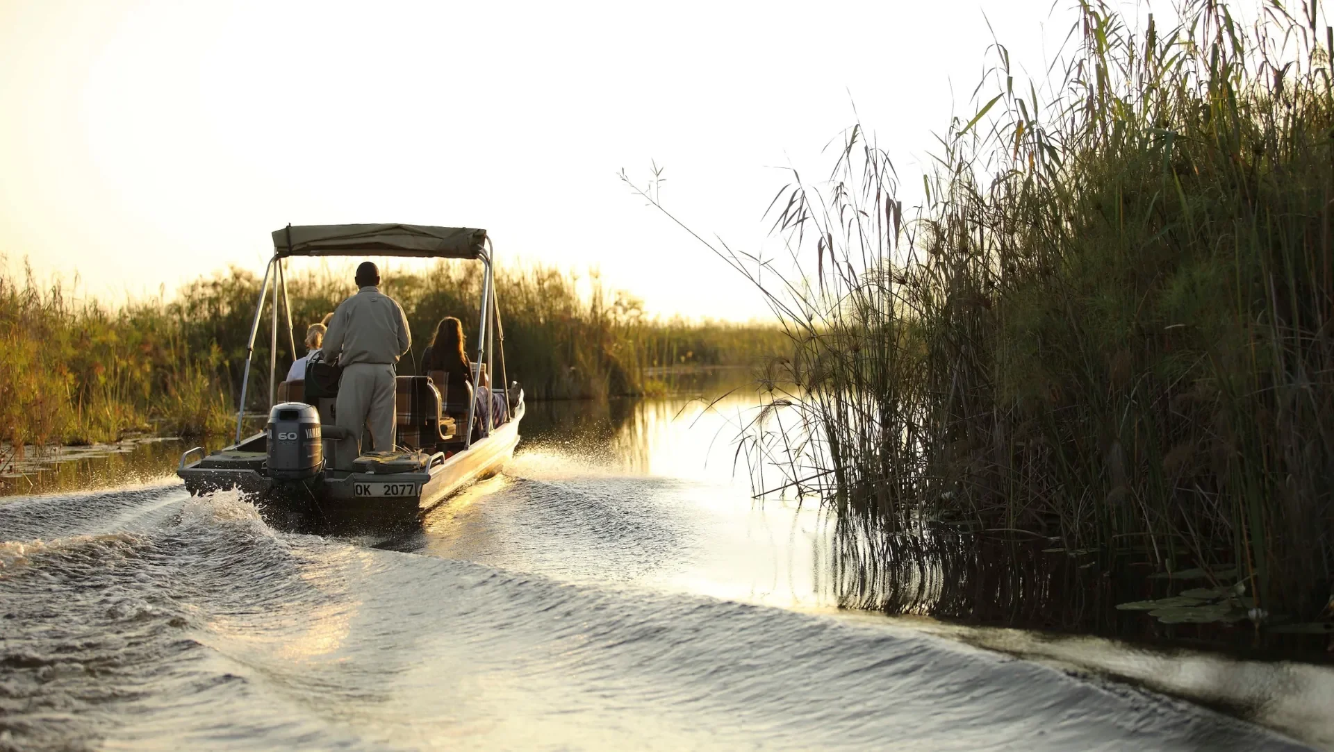 Okavango Delta boat cruise at sunset, tranquil channels and papyrus banks