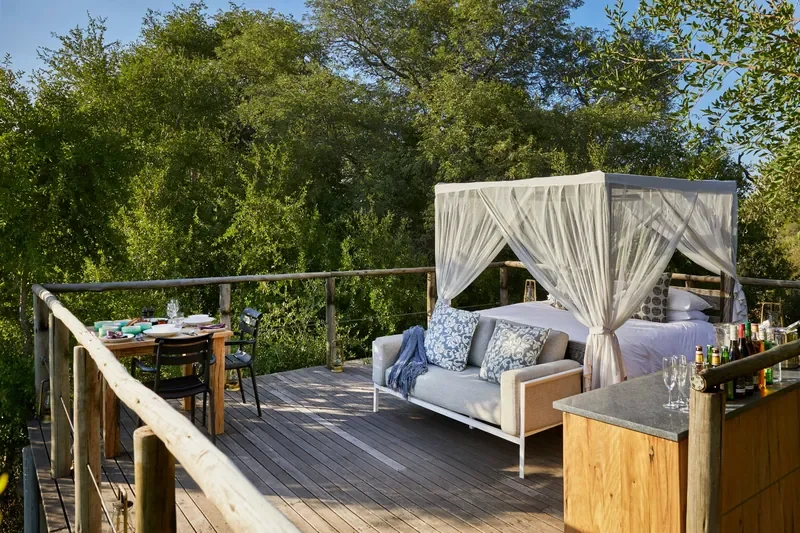 Canopy bed and private bar on the Tinyeleti Treehouse deck surrounded by riverine trees, Lion Sands.