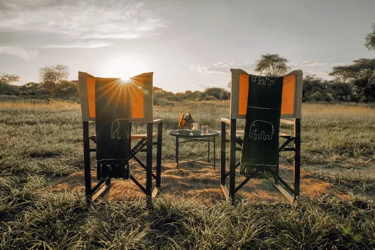 Sundowner chairs facing sunset at Little Chem Chem with a small campfire on the plains