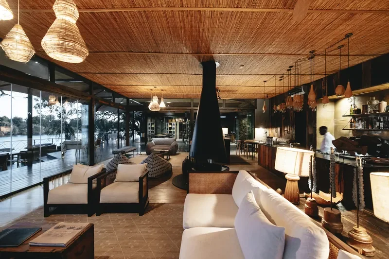 Warm lounge and bar interior at Thorntree River Lodge with central fireplace, Zambia