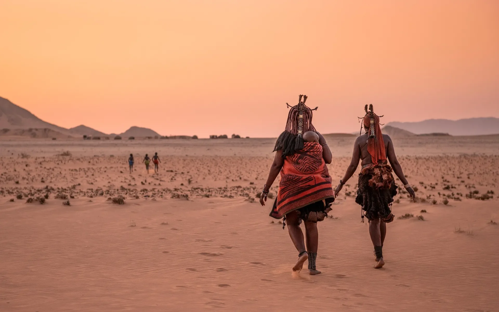 Himba women walking at sunset across the Namib Desert near Serra Cafema, cultural immersion in Namibia