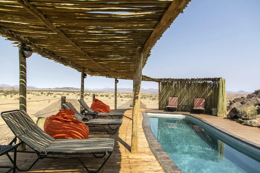 Shaded pool deck at Wilderness Doro Nawas with wide desert panorama, Damaraland, Namibia