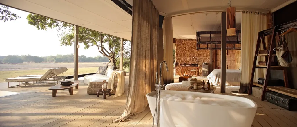 Light-filled suite with freestanding bath and lounge area at Time + Tide Chinzombo, contemporary safari tent in South Luangwa