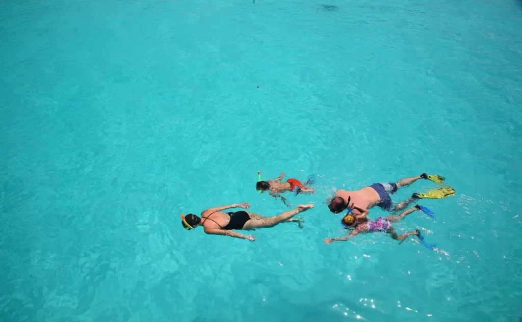 Family snorkelling in clear lagoon – Mnemba Island, Zanzibar, Tanzania