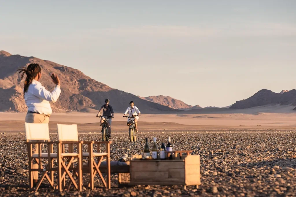 Kulala Desert Lodge sundowner setup with guests arriving on e bikes