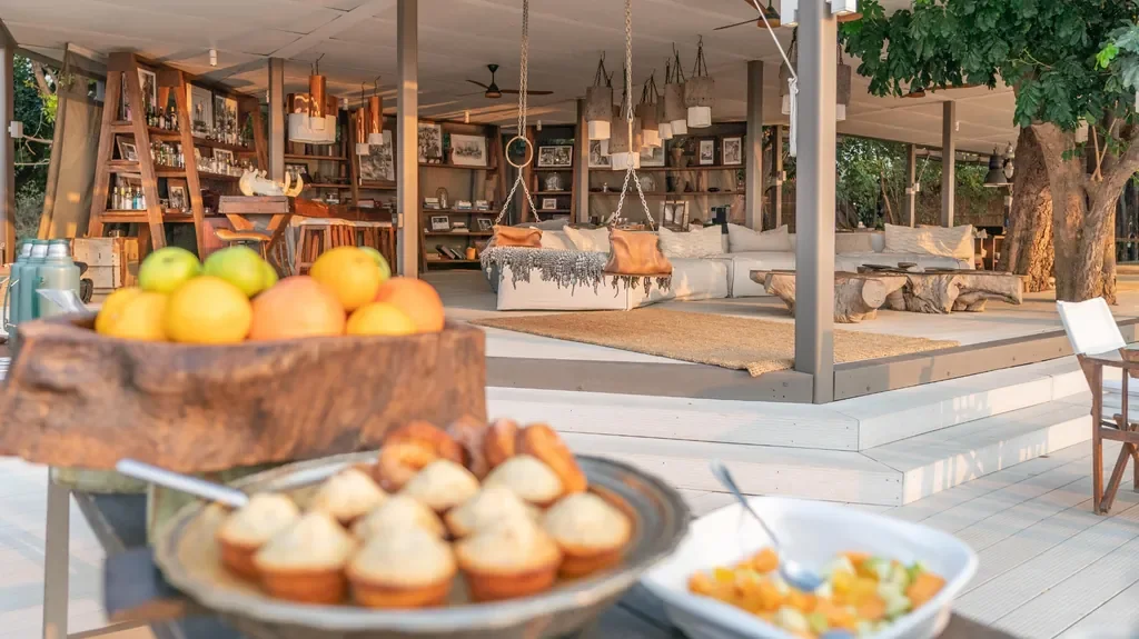 Breakfast setup with fruit and muffins facing the lounge and bar at Time + Tide Chinzombo, South Luangwa National Park, Zambia