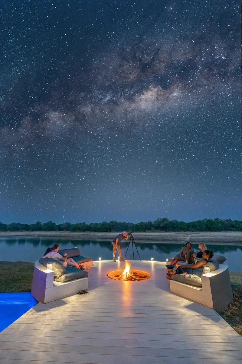 Stargazing around the firepit deck at Time + Tide Chinzombo beside the Luangwa River, luxury safari evening, South Luangwa, Zambia