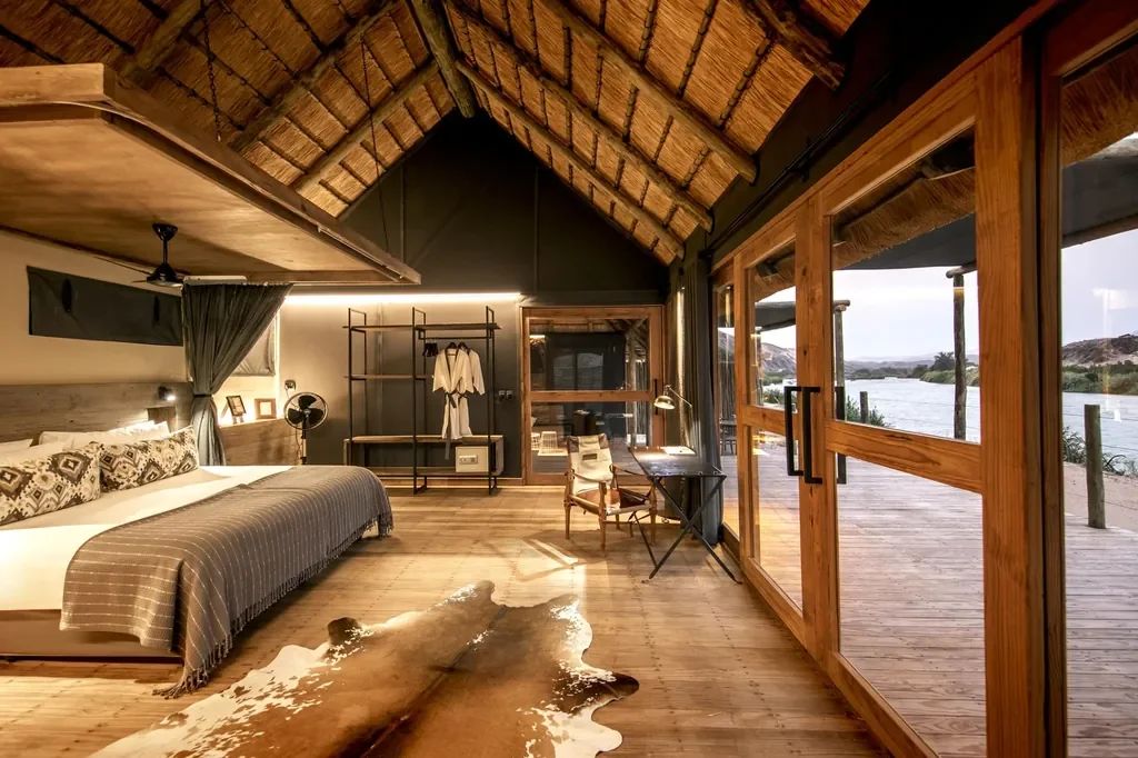 Serra Cafema riverfront suite interior with thatched roof and private deck, Kunene Namibia