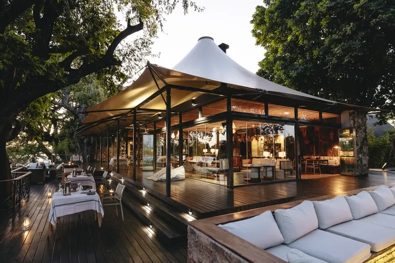 Glass-walled main lodge pavilion at Thorntree River Lodge, lantern lit deck on the Zambezi, Zambia