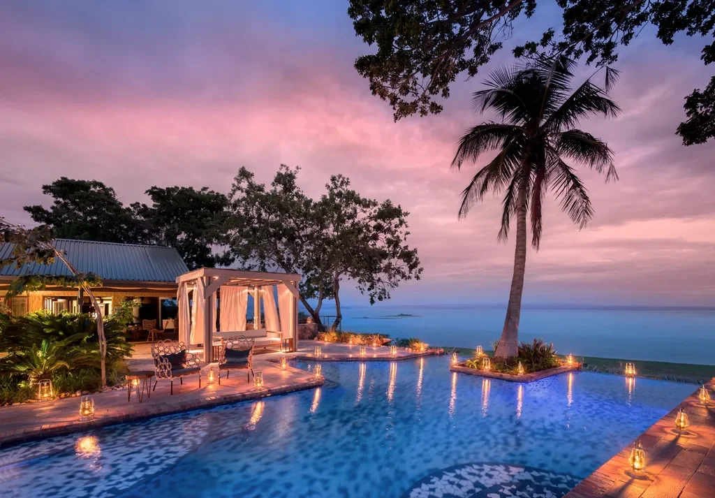 Lantern-lit infinity pool and cabana at Bumi Hills Safari Lodge with panoramic Lake Kariba views at twilight, Zimbabwe
