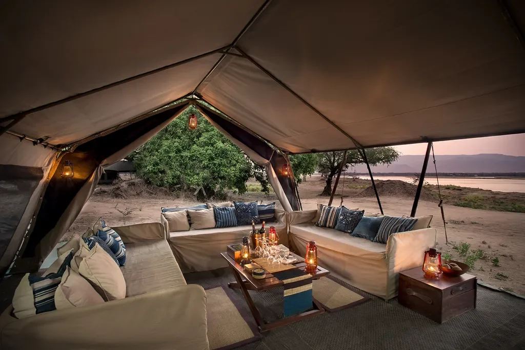 Open-air lounge tent with canvas sofas and lanterns by the Zambezi, Zambezi Expeditions