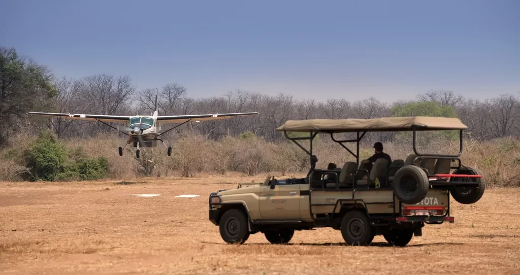 Light aircraft landing at Mana Pools airstrip with Kanga Expeditions game drive vehicle, Zimbabwe