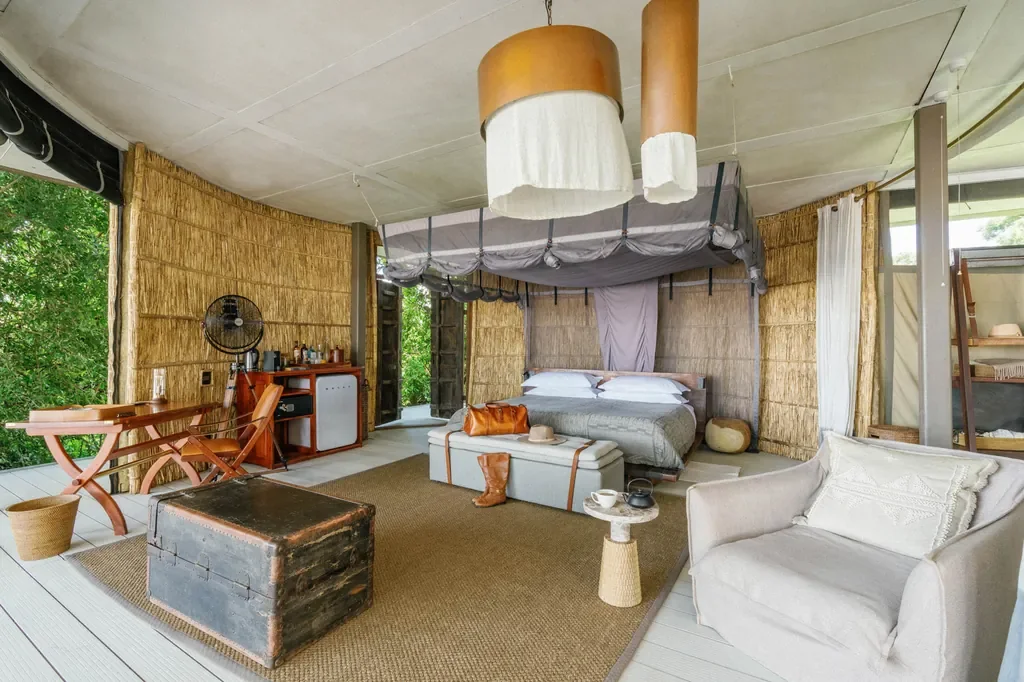 Suite interior at Time + Tide Chinzombo with canopy mosquito net, woven reed walls and private lounge, luxury safari accommodation in South Luangwa, Zambia