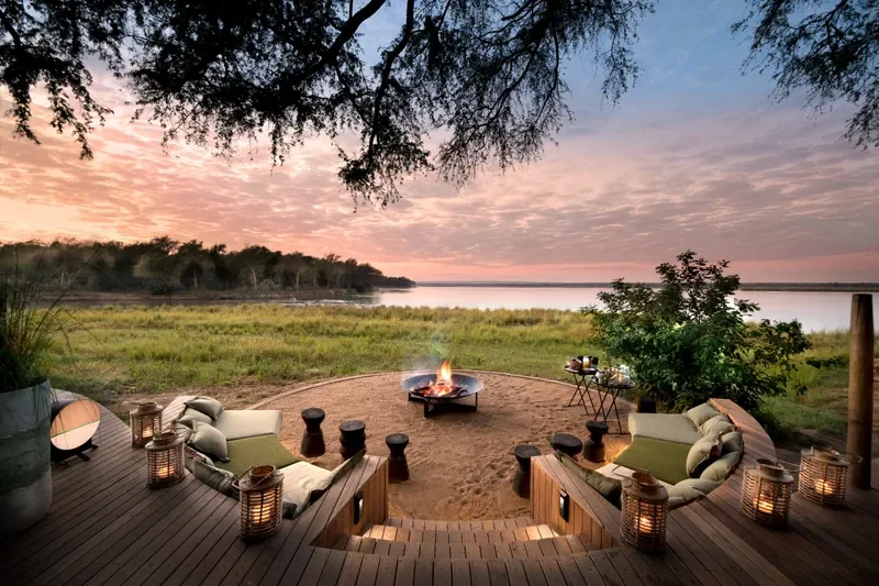 Circular firepit lounge facing the Zambezi River at Lolebezi Lodge, sunrise colours over Lower Zambezi National Park, Zambia, Nomara