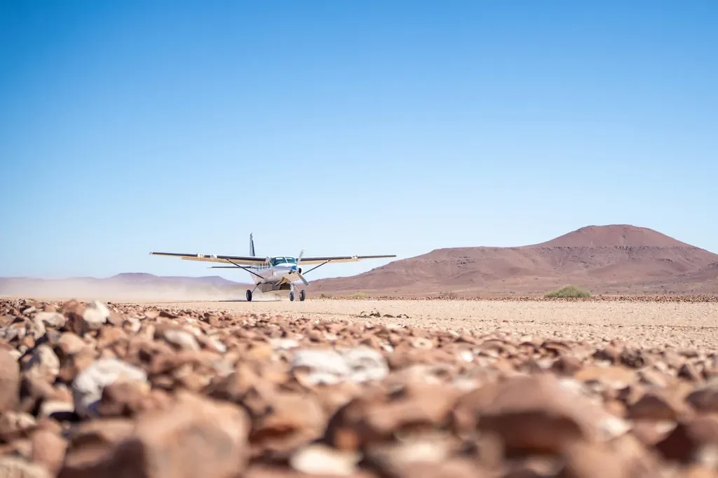 Light aircraft landing on the Desert Rhino Camp gravel airstrip for fly-in safaris, Damaraland Namibia