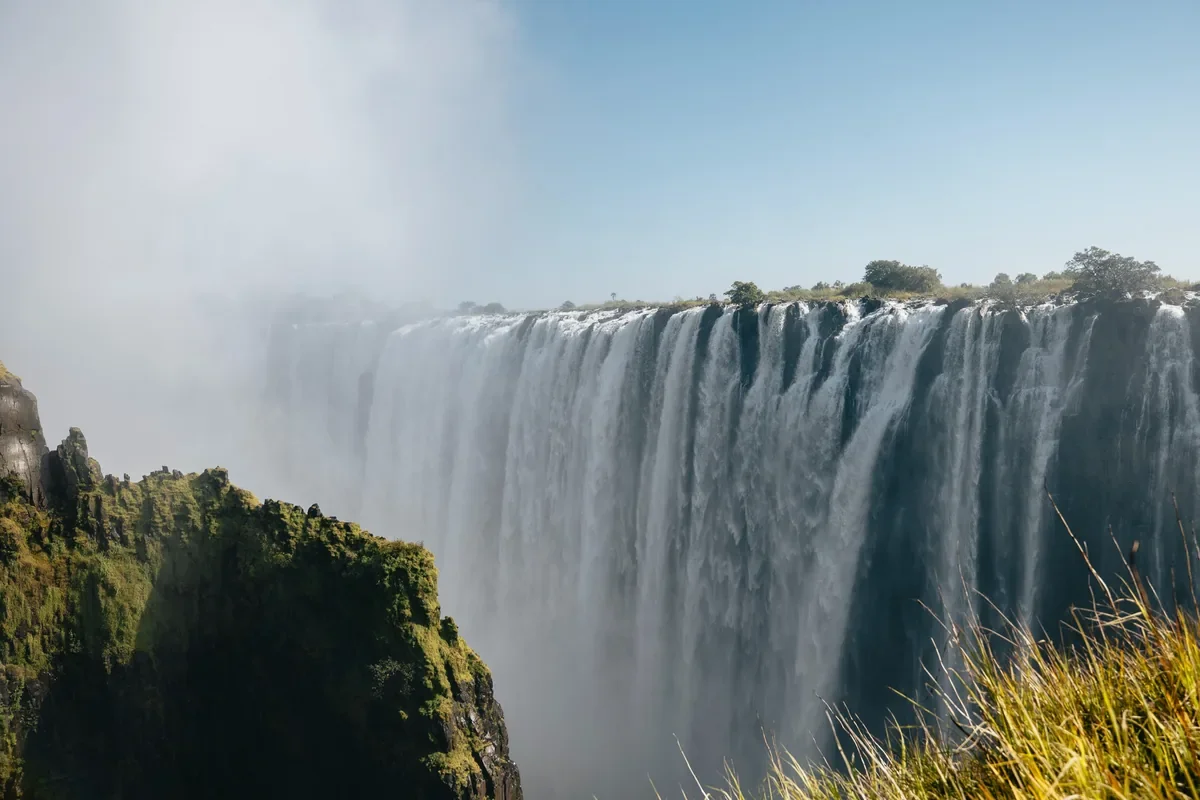 Victoria Falls in the distance with mist rising into a clear sky