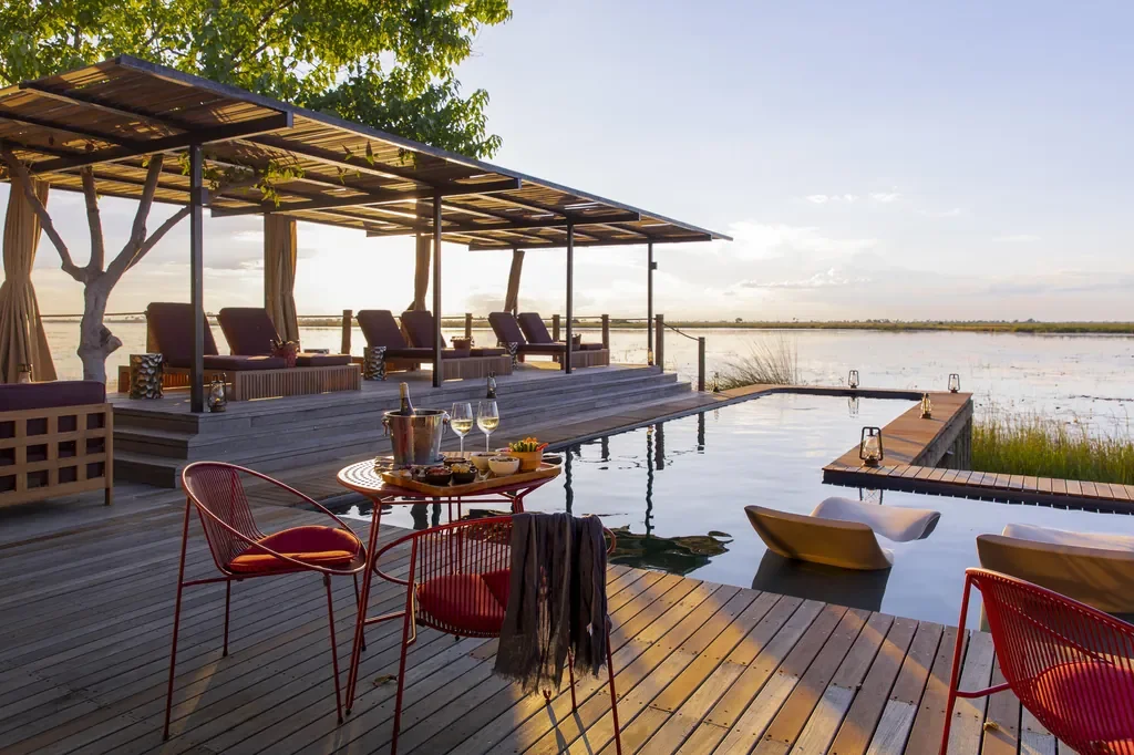 Main pool deck at DumaTau with cabanas, loungers and water-level views across the Linyanti