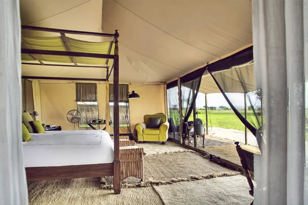 Tented room interior at Little Chem Chem with four poster bed and lounge, Lake Burunge Tanzania
